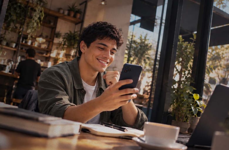 Persona usando su celular en una cafetería